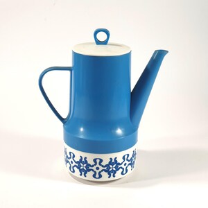 May include: A blue and white ceramic coffee pot with a floral design. The pot has a white lid with a handle and a blue spout.