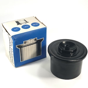 Może przedstawiać: Czarny zbiornik do wywoływania filmów z pasującym pudełkiem. Pudełko jest niebiesko-białe z napisem "flex-Universal" i schematem zbiornika. Zbiornik jest cylindryczny z pokrywką.