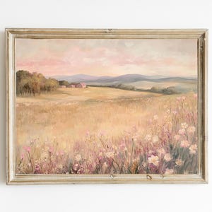 May include: A framed landscape painting with a serene meadow scene. The artwork features a field of wildflowers in shades of pink and white, with a backdrop of rolling hills and a soft, pastel sky. The frame is a light, neutral color.
