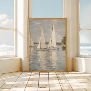 May include: A framed painting of sailboats on a body of water. The artwork features three sailboats with white sails, reflecting in the water. The sky is a pale blue, and the painting is in a wooden frame. The scene evokes a sense of tranquility.