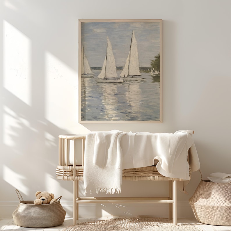 May include: A framed print of sailboats on water, with white sails and a light blue sky. The artwork is displayed above a wooden bench with a white blanket and a woven basket with a teddy bear.