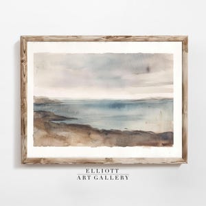 May include: A watercolor painting of a seascape with a light blue ocean, brown shoreline, and a cloudy sky. The painting is framed in a light brown wooden frame.