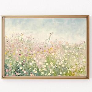 Op de afbeelding: Een ingelijst schilderij van een veld met wilde bloemen in tinten roze, wit en groen. De achtergrond is een zacht blauw met een wazig aquareleffect.