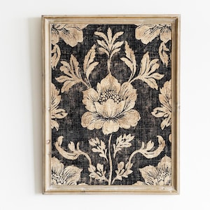 Puede incluir: Impresión floral enmarcada con un patrón repetido de grandes flores y follaje estilizado en tonos beige y dorado sobre un fondo oscuro y texturizado. La impresión está encerrada en un marco de madera de color claro.