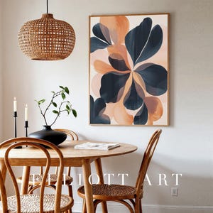 May include: Abstract floral art print in a wooden frame. The artwork features large, stylized flower shapes in shades of navy blue, peach, and blush pink. The print is displayed above a round wooden dining table with matching chairs. The text "ELLIOTT ART" is visible.