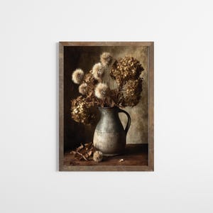 May include: A framed print depicting a still life of dried flowers in a grey, rustic jug. The arrangement includes large, dried hydrangeas and fluffy seed heads. The artwork is set against a neutral background, with a wooden table and frame.