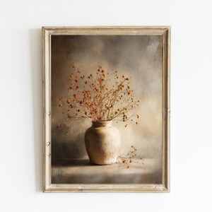 May include: A framed print featuring a still life of dried flowers in a beige vase. The artwork has a vintage aesthetic with a neutral color palette of beige, brown, and muted orange. The frame is a light, distressed wood.