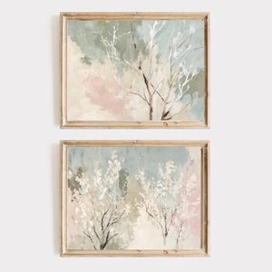 May include: A set of two framed abstract paintings featuring delicate white branches against a soft blue and pink background. The paintings have a light and airy feel, perfect for adding a touch of nature to any room.