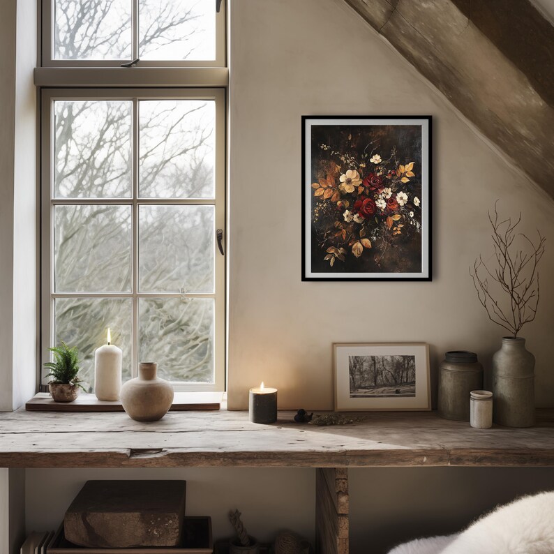 K&ouml;nnte beinhalten: Ein gerahmter Blumendruck mit einem Bouquet aus roten, wei&szlig;en und gelben Blumen vor einem dunklen Hintergrund. Das Kunstwerk h&auml;ngt an einer beigefarbenen Wand &uuml;ber einem Holzregal mit Kerzen und dekorativen Gegenst&auml;nden. Links ist ein Fenster mit Blick auf kahle B&auml;ume.