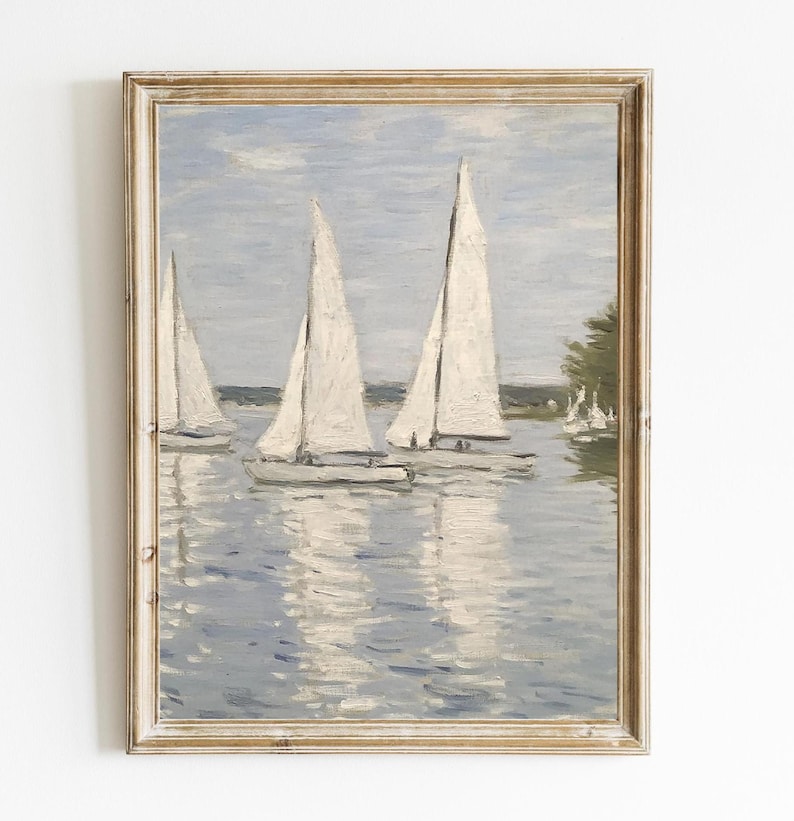 May include: A framed painting depicts sailboats on a calm body of water. The sailboats have white sails and are reflected in the water. The painting has a muted color palette of blues, whites, and greens, with a gold-toned frame.