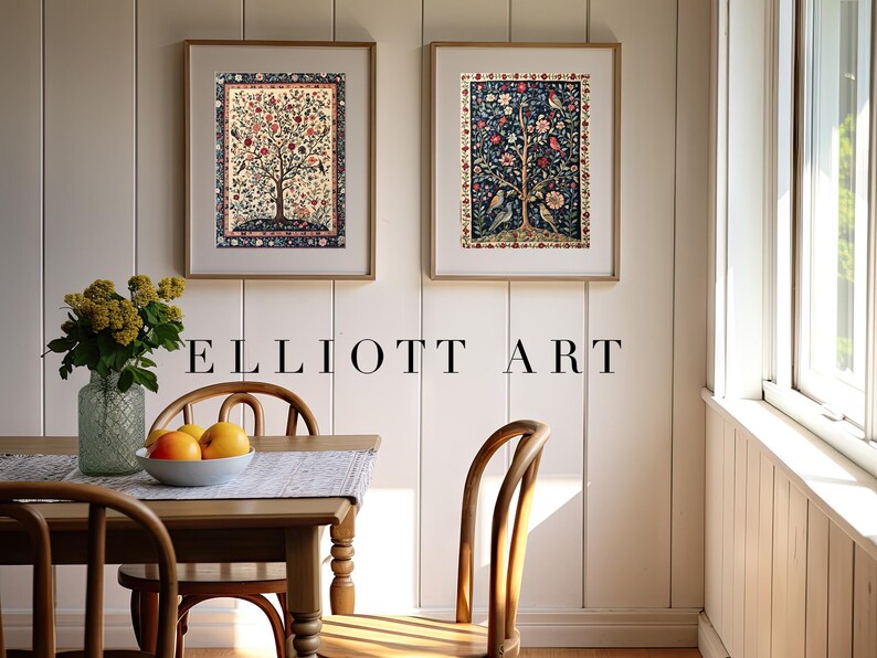 May include: Two framed art prints with tree and bird designs hang on a white wall. The prints are in gold frames. A wooden table with a vase of flowers and a bowl of fruit sits below the art. The text "ELLIOTT ART" is below the art prints.