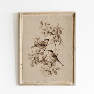 May include: A framed sepia-toned print featuring two birds perched on a flowering branch. The birds are depicted in a detailed, vintage style, with delicate lines and shading. The artwork is set against a neutral background, and the frame has a distressed, antique appearance.