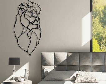 May include: Black metal wall art depicting a stylized lion's head. The art is mounted on a white wall above a gray upholstered headboard.