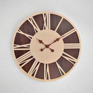 May include: A large, round, wooden wall clock with Roman numeral markings and brown wood accents. The clock face is light beige with brown hands.