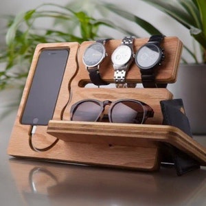 May include: Wooden organizer with slots for watches, sunglasses, and a phone. The organizer is made of light brown wood and has a natural finish.