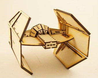 May include: A wooden model of a TIE fighter, a spacecraft from a science fiction franchise. The model is constructed from light-colored wood, with detailed cutouts and geometric shapes. The wings are angled, and the central body features intricate designs.