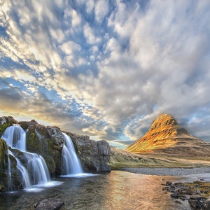 Kirkjufell e Kirkjufellsfoss in Islanda al tramonto con nuvole brillanti