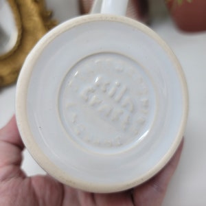 May include: White ceramic mug with a white logo that reads "Griffin  Paris" on the bottom.