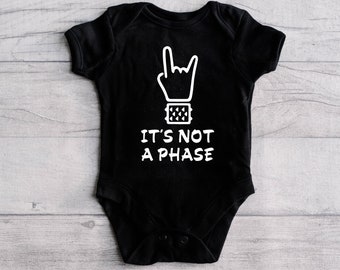 May include: Black baby onesie with a white graphic of a hand making a rock and roll sign with the text "It's not a phase".