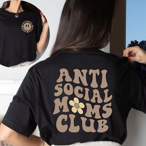 May include: Black t-shirt with a brown graphic on the back that says "Anti Social Moms Club" with a yellow flower in the middle of the word "Moms".
