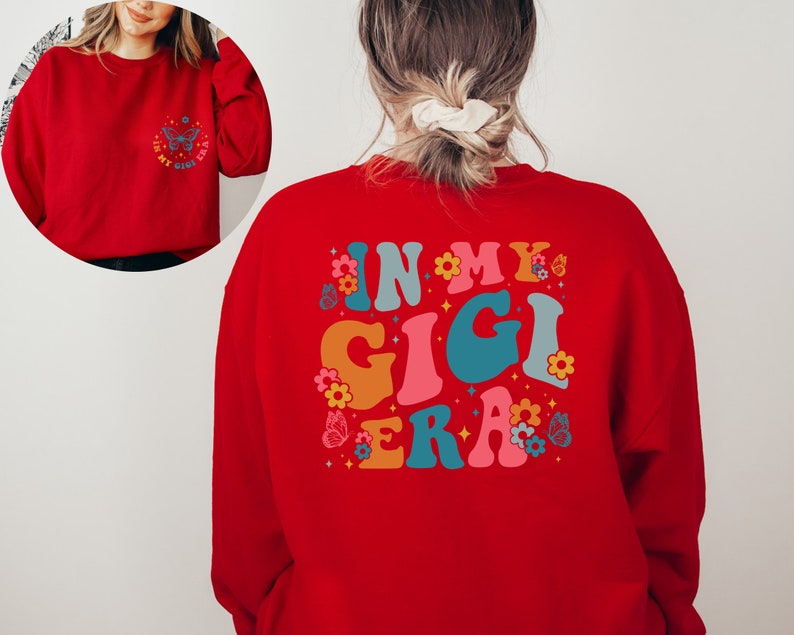 May include: Red sweatshirt with the text "In My Gigi Era" in colorful retro font with butterflies and flowers.