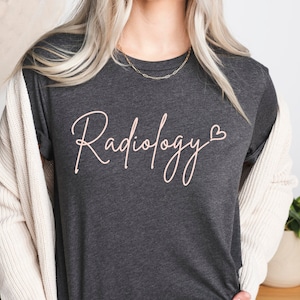 May include: A dark gray t-shirt with the text "Radiology" in a white cursive font with a small heart symbol after the word.