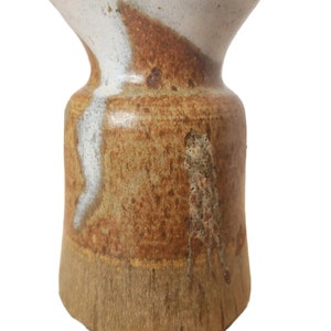 May include: A brown and white ceramic vase with a textured glaze. The vase has a wide mouth and a narrow base.