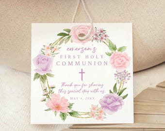 May include: A white card with a floral wreath border and a purple cross. The text reads "emerson's First Holy Communion" and "Thank you for sharing this special day with us May 4, 20xx".