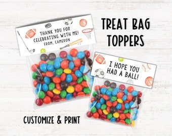 May include: Two white treat bag toppers with a sports theme. The top topper says "Thank you for celebrating with me! From, Cameron" and the bottom topper says "I hope you had a ball!" Both toppers feature a variety of sports equipment including a baseball, basketball, football, golf club, tennis racket, and soccer ball.