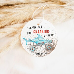 May include: Round white thank you tag with blue and red monster truck illustration. The tag says "Thank you for crashing my party from Lucas".
