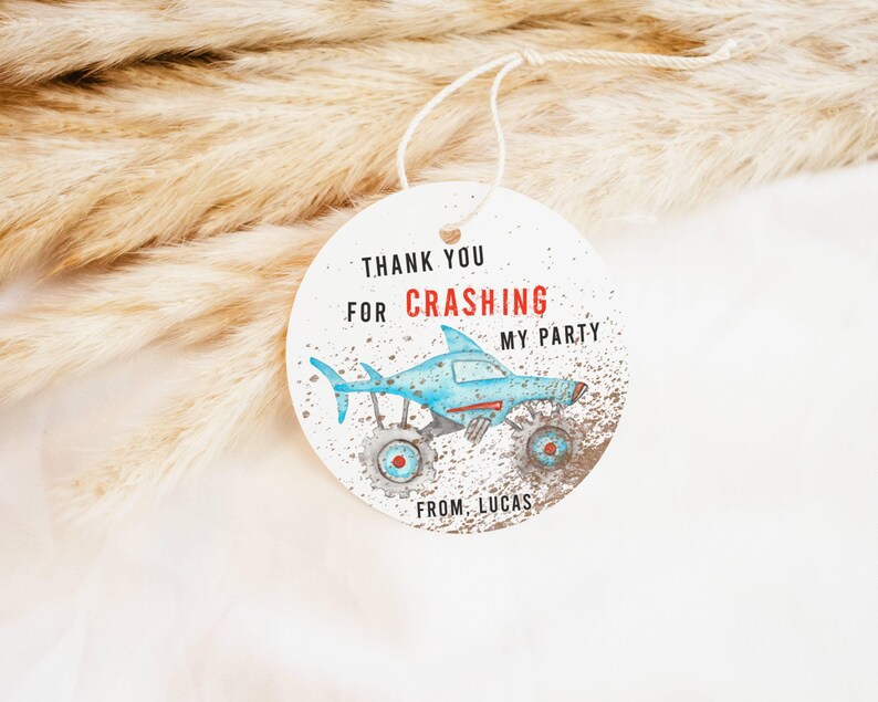 May include: Round white thank you tag with blue and red monster truck illustration. The tag says "Thank you for crashing my party from Lucas".