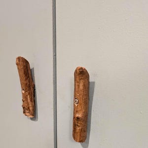 Peut inclure: Deux boutons de porte en bois avec une finition brun naturel. Les boutons sont en forme de branches et ont un aspect rustique.