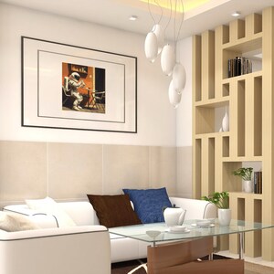 May include: A white sectional sofa with brown and blue throw pillows sits in front of a glass coffee table. A wooden room divider with shelves is to the right of the sofa. A framed picture of an astronaut sitting on a chair is hanging on the wall.