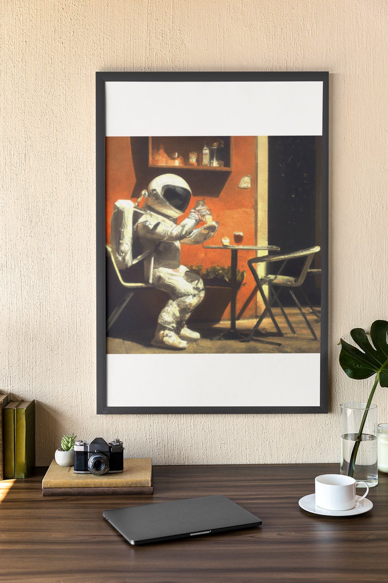May include: A framed illustration of an astronaut sitting at a table outside a cafe, drinking from a glass. The astronaut is wearing a white spacesuit and a helmet. The cafe is painted in warm colors with a red wall and a green plant.