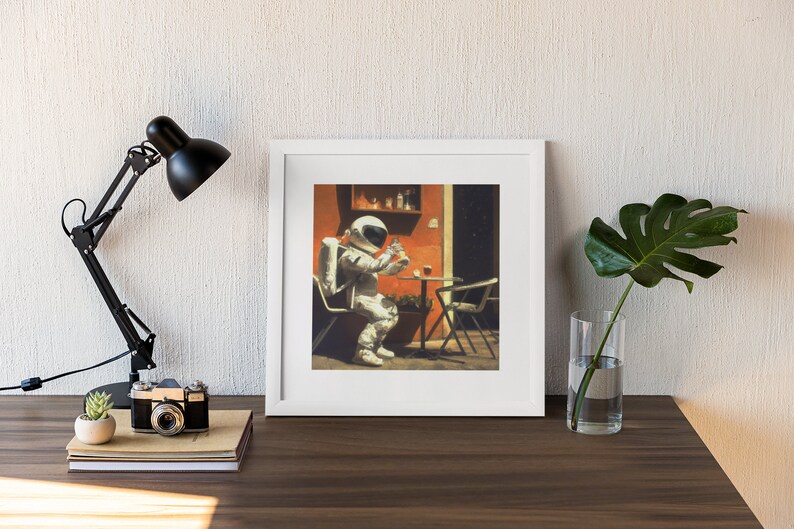 May include: A framed print of a painting depicting an astronaut sitting at a table outside a building, holding a cup. The astronaut is wearing a white spacesuit with a backpack. The building is painted orange and has a window with a view of stars. The table is brown and has a glass of liquid on it. There is a green plant in a pot on the table.