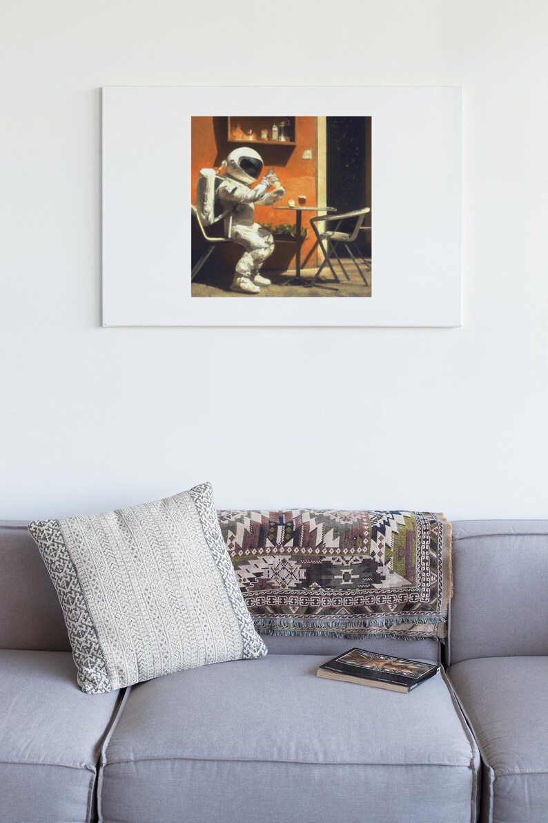 May include: A white astronaut in a spacesuit sits at a table with a glass of liquid in their hand. The astronaut is sitting in a chair with a red and orange wall behind them.