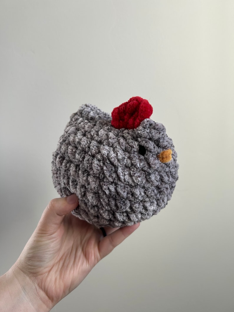 May include: A gray crocheted chicken toy with a red comb and a yellow beak.