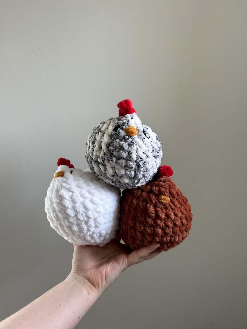May include: Three crocheted chicken toys. One is white, one is brown, and one is black and white.