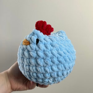 May include: A light blue crocheted chicken toy with a red comb and orange beak.