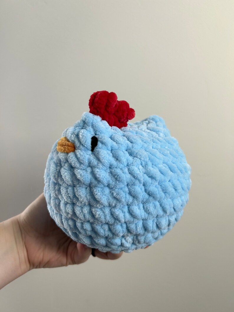 May include: A light blue crocheted chicken toy with a red comb and orange beak.