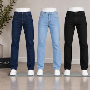 Peut inclure: Trois paires de jeans en denim présentées sur des mannequins blancs. La paire de gauche est bleu indigo foncé, la paire centrale est bleu clair et la paire de droite est noire. Chaque paire présente une coupe à cinq poches, un bouton et une braguette.