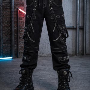 May include: Black cargo trousers with white stitching, chains, and studded details. The trousers have multiple pockets and straps with metal hardware. The model is wearing black platform boots with metal accents, creating a gothic or punk aesthetic.
