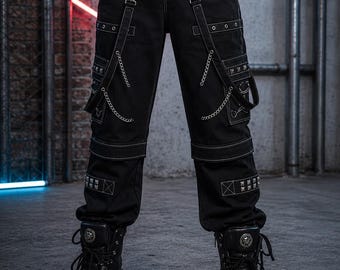 May include: Black cargo pants with white stitching, chains, and studded accents. The pants feature multiple pockets and straps with metal hardware. The model is wearing black platform boots with metal details, creating a gothic or punk aesthetic.