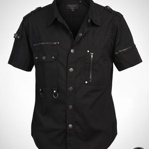 May include: Black short-sleeve shirt with multiple pockets, zippers, and metal button details. The shirt has a collared neckline and epaulettes on the shoulders. The brand name "Dark Land" is visible in the bottom right corner.