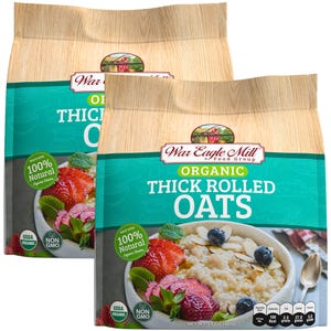 May include: Two bags of War Eagle Mill Organic Thick Rolled Oats, each bag is 24 ounces (680 grams). The bags are brown with a green and blue design. The front of the bag features a bowl of oatmeal with strawberries, blueberries, and almonds. The text "Made with 100% Natural Organic Grains" is on the bag.
