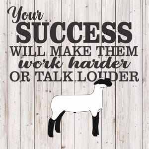 May include: A motivational sign with the text "Your SUCCESS WILL MAKE THEM work harder OR TALK LOUDER" in black font. A white sheep with black legs and head is below the text. The background is a light wood grain.
