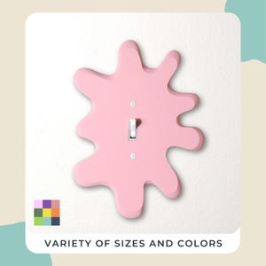 May include: A light pink, splash-shaped light switch cover with a silver toggle switch and two screws. The cover is mounted on a white wall. The text "VARIETY OF SIZES AND COLORS" is at the bottom.