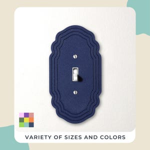 Peut inclure: Un cache-interrupteur bleu marine décoratif avec un bord festonné. Il comporte un interrupteur à bascule standard et est monté sur un mur blanc. Le texte "VARIÉTÉ DE TAILLES ET DE COULEURS" est affiché en bas.