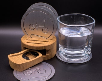 May include: Set of four silver metal coasters with a bicycle design, a wooden coaster holder with a bottle opener, and a glass of water on a silver metal coaster.