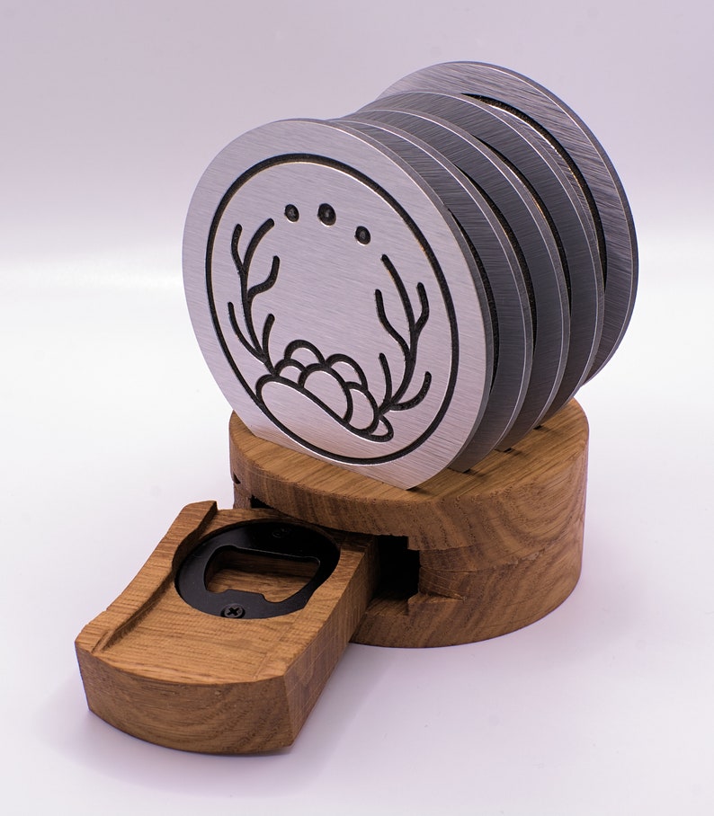 May include: A set of six silver coasters with a black antler design and three dots. The coasters are stacked on a wooden base with a built-in bottle opener.